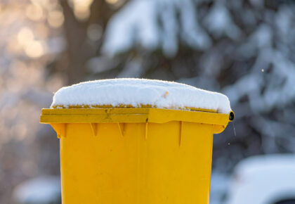 Vue d'un bac jaune de déchets recyclables sous la neige